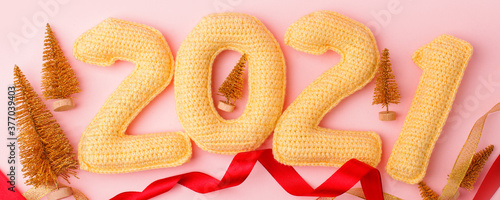 Happy new year 2021. Christmas or new year decorations on pink pastel background. Christmas background with yellow crocheting numbers 2021 and seasonal decor, flyer for your promotion photo