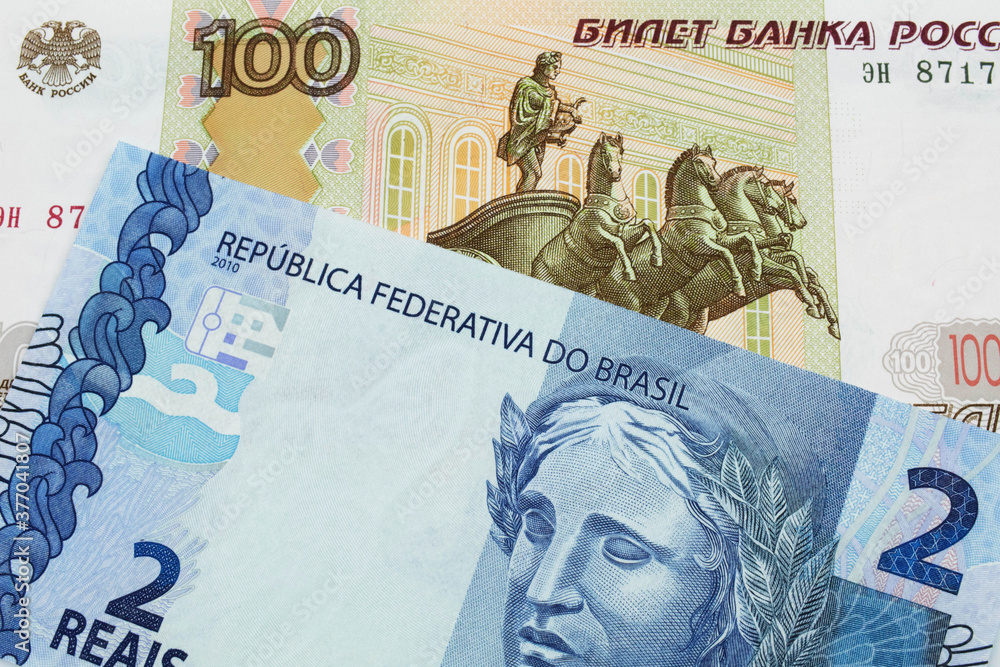 Obraz premium A macro image of a Russian one hundred ruble note paired up with a blue two real bank note from Brazil. Shot close up in macro.