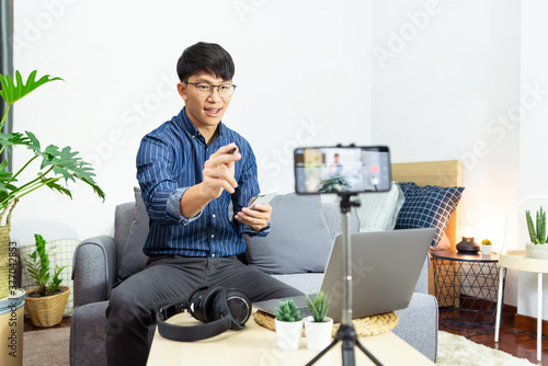 Social media influencer or blogger present and review recording or streaming vlog about product using smartphone on tripod for social media channel making live stream concept. photo