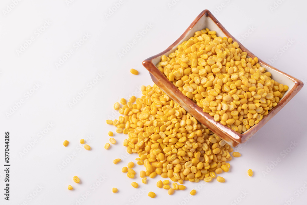 Hulled split mung bean in brown cup on white background Hulled split mung bean in brown cup on white background