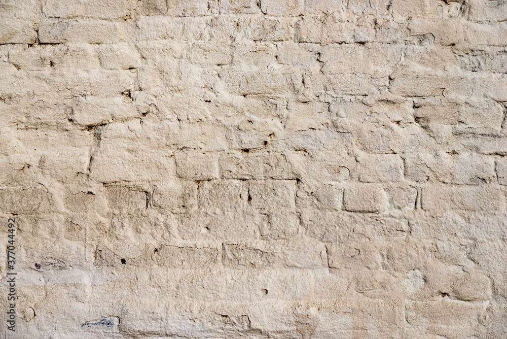 The texture of the old brick wall painted white with peeling paint
