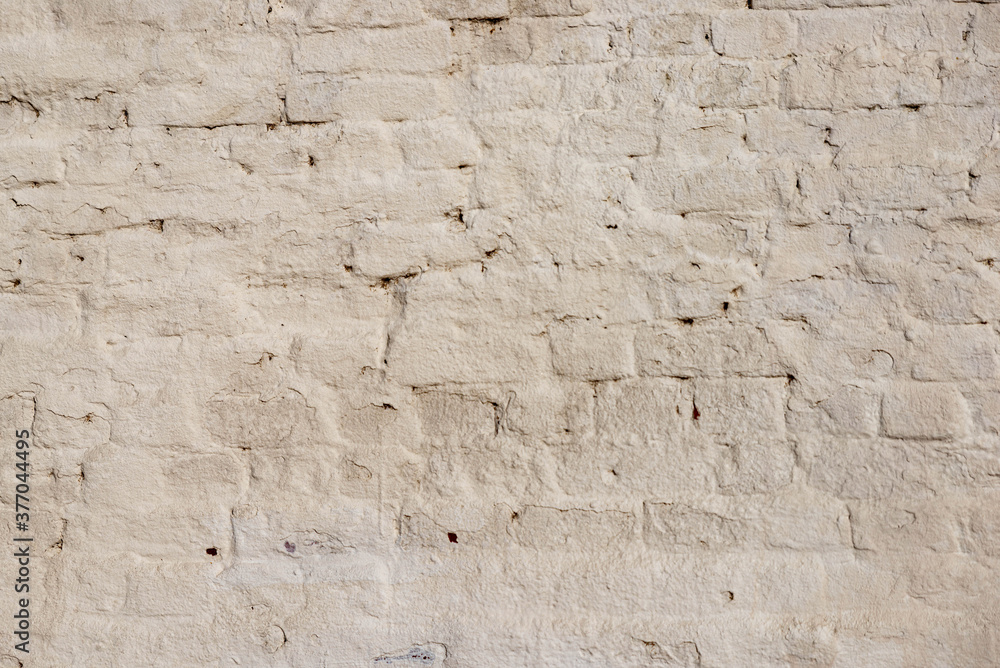 The texture of the old brick wall painted white with peeling paint