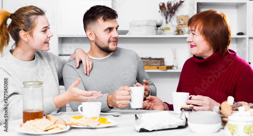 Portrait of happy family enjoying conversation over cup of coffee at home