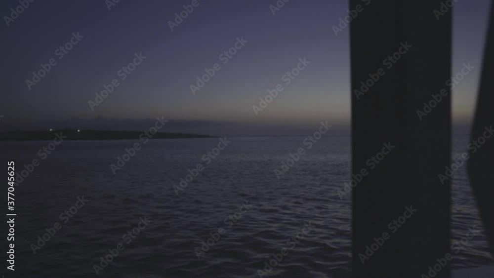 The ocean, the sky and an island is seen from a window of a room. The ocean, the sky and an island is seen from a window of a room.
