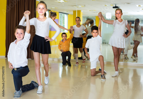Smiling kids are dancing waltz in class.
