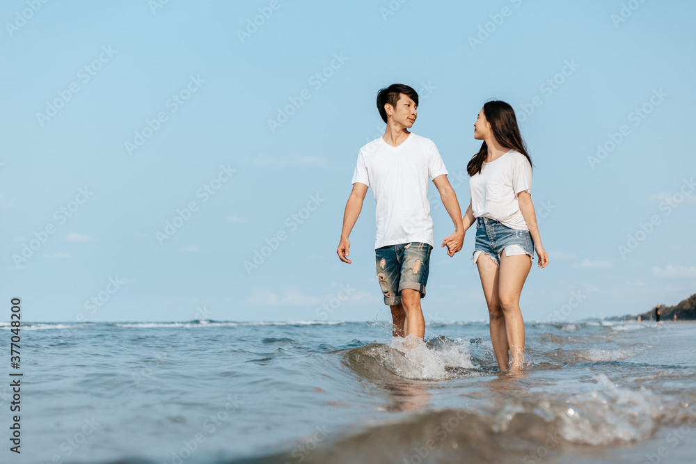 Romantic couple holding hands and walking on beach. Man and woman in love.