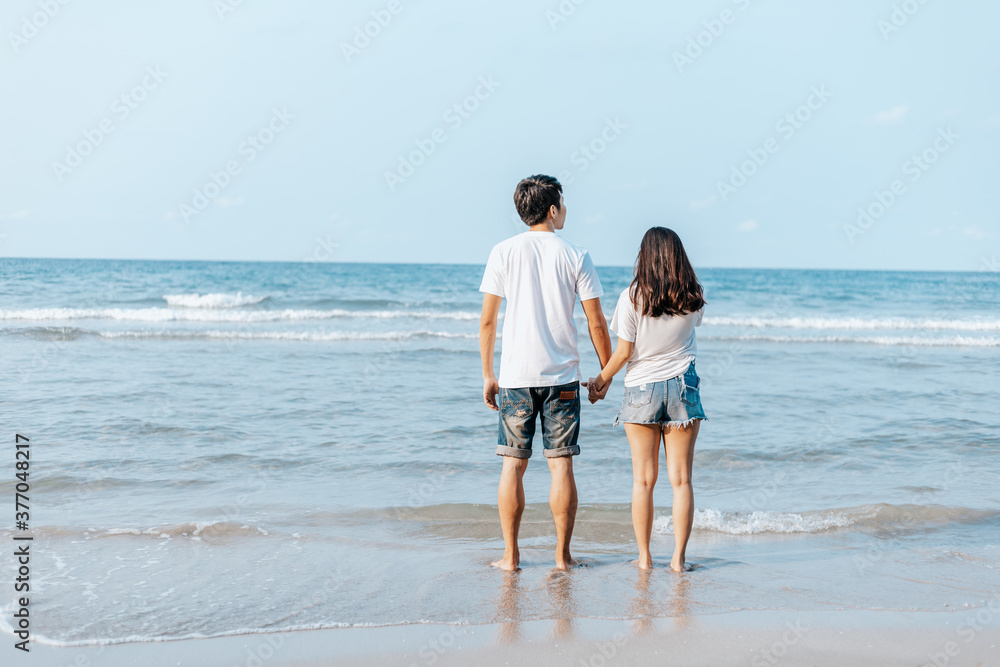Romantic couple holding hands and stand together on beach. Man and woman in love.