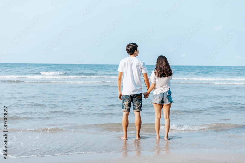 Romantic couple holding hands and stand together on beach. Man and woman in love. Romantic couple holding hands and stand together on beach. Man and woman in love.