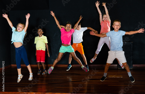 Positive children jumping while studying modern style dance in the class in the evening