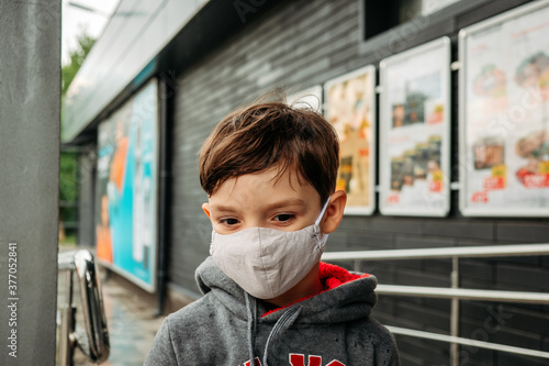 A boy in a protective mask enters the supermarket. Protecting a child from covid-19 coronavirus in a supermarket.