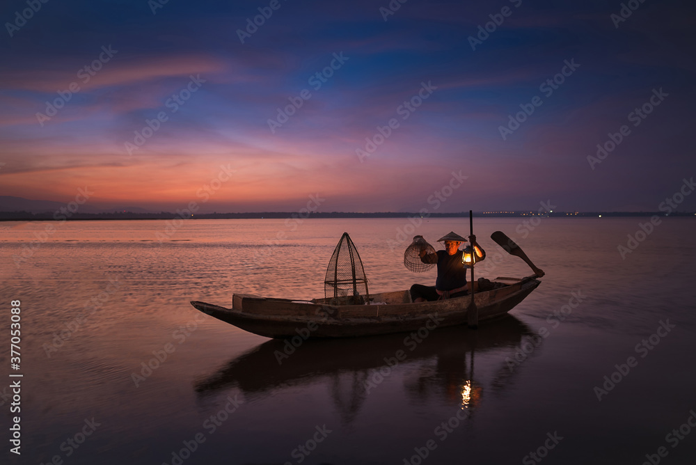 Asian fisherman with his wooden boat in nature river at the early morning before sunrise