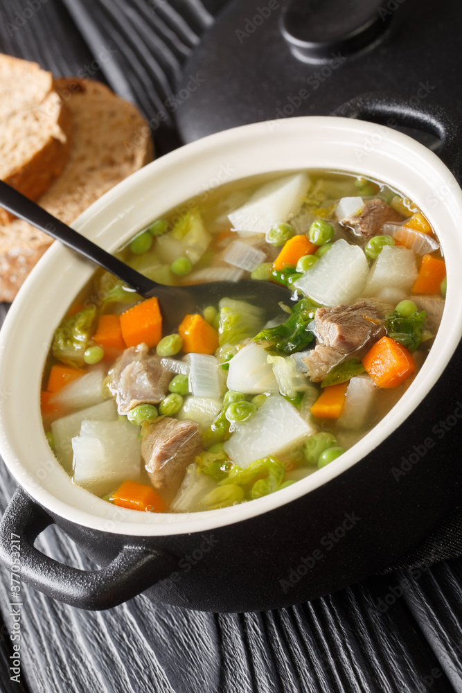 Tradtional Scottish Harvest Broth called Hotch Potch with lamb meat close-up in a pot on the table. Vertical