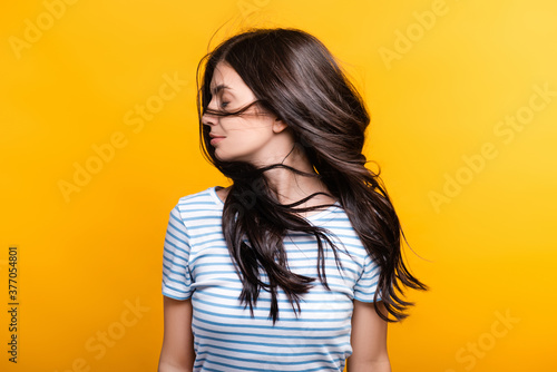 brunette woman with curls waning hair isolated on yellow
