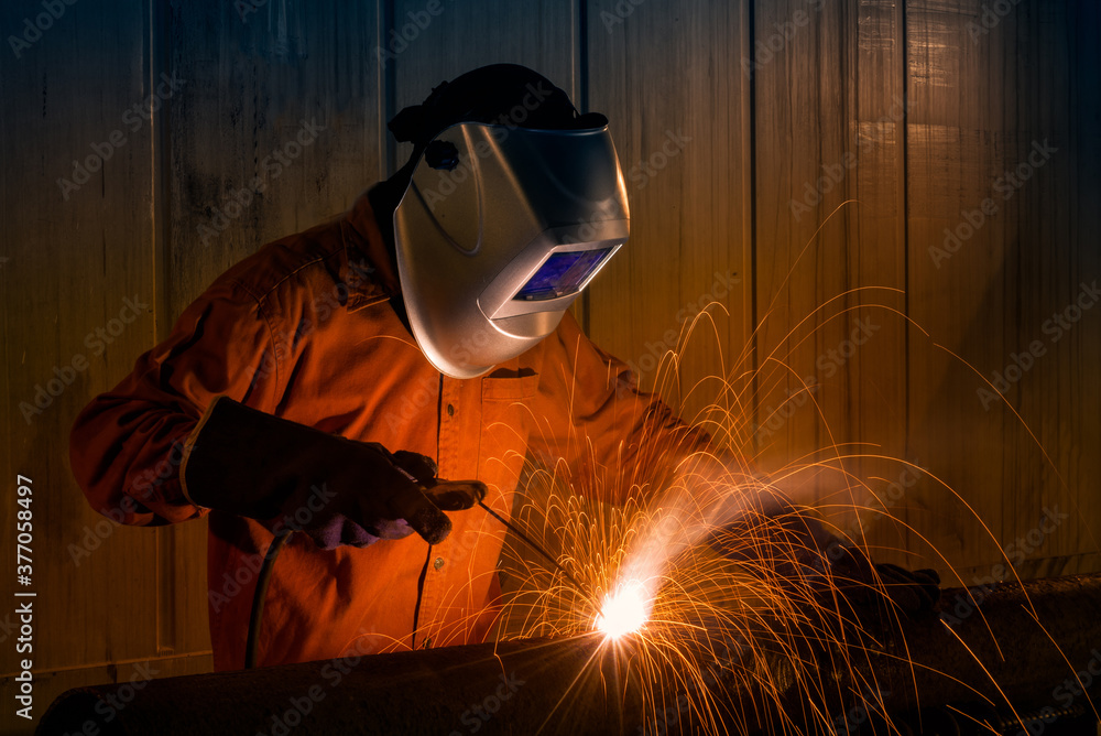 Industrial Worker with safety equipments and protective mask welding steel structure in construction factory. Industrial Worker with safety equipments and protective mask welding steel structure in construction factory.