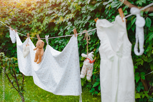 children's clothing and a toy Teddy bear on a clothesline is dried after being washed outdoors in the backyard