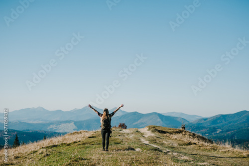 Hiker with backpack relaxing on top of a mountain. Woman enjoying the sunrise.