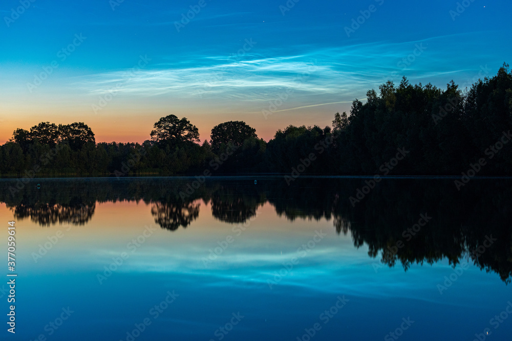 Leuchtende Nachtwolken über einem See in Deutschland