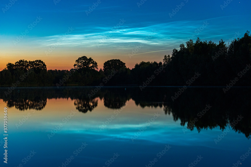 Leuchtende Nachtwolken über einem See in Deutschland Leuchtende Nachtwolken über einem See in Deutschland