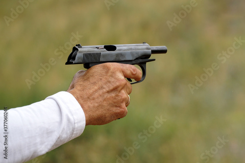 Man's hand with a white sleeve and with a gun.