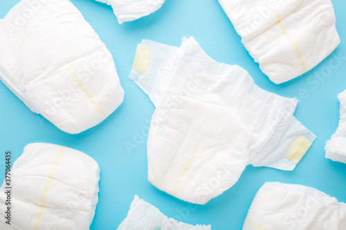Many white baby diapers on light blue table background. Pastel color. Top down view. Closeup. photo