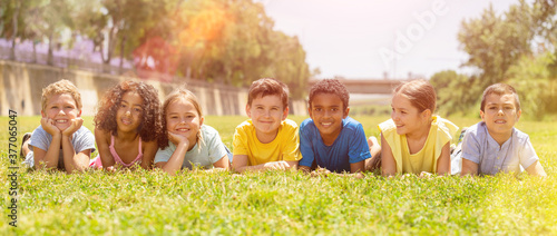 Group of school children resting on grass and smiling together in park © JackF