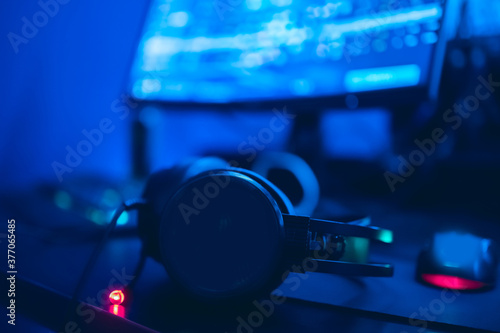 Selective focus on professional gaming computer headphones with microphone, streamer workplace in background