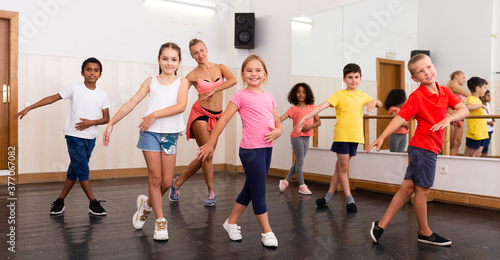 Group of tweens doing dance workout with female coach in classic choreography class..