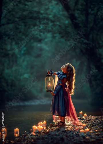Girl in dress with lantern in a dark forest photo