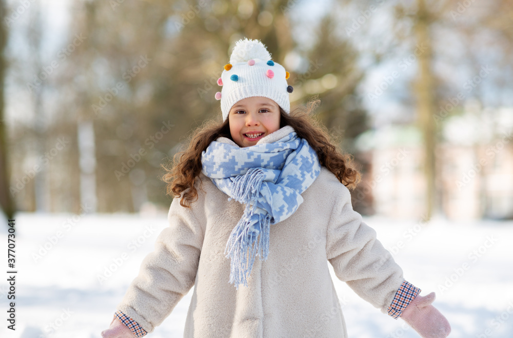 Obraz premium childhood, leisure and season concept - portrait of happy little girl in winter clothes outdoors at park
