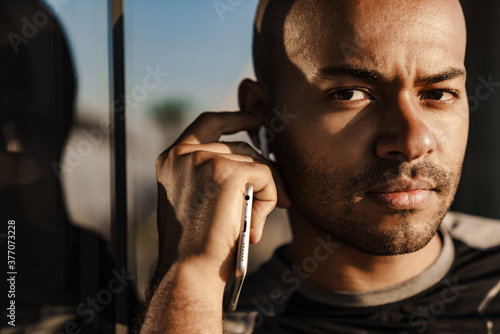 Image of sportsman using wireless earphones while holding cellphone