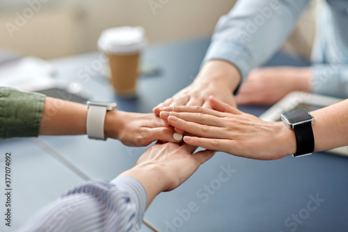 cooperation, corporate and team work concept - close up of business team stacking hands at office