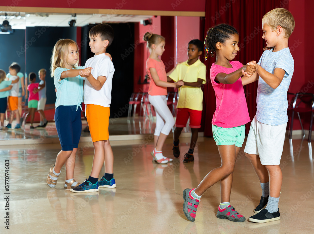 Group of cheerful kids dancing salsa dance in modern studio