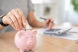 savings and finance. women put coin into the piggy bank