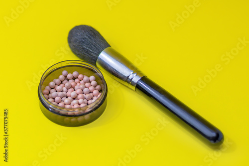 Makeup blush and brush close-up, shallow depth of field, blur. Bright yellow background