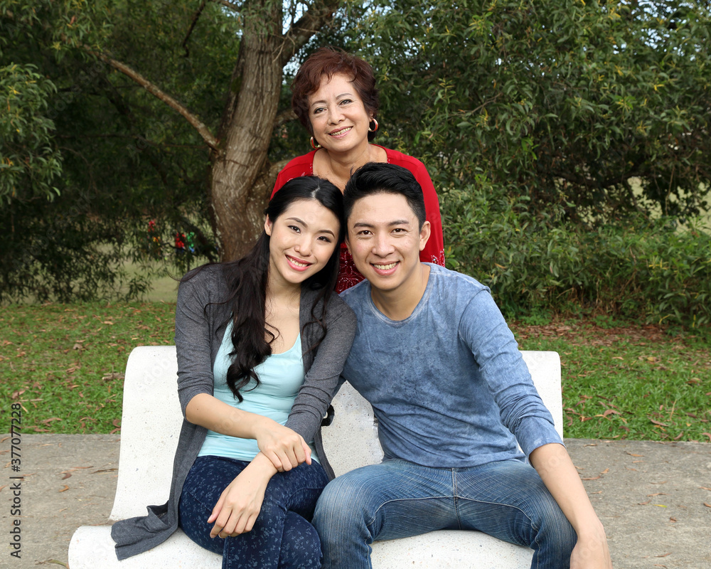 Naklejka premium Southeast Asian family adult senior parents mother son daughter sit on park bench happy at outdoor park