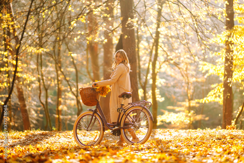 Autumn woman in autumn park. Happy young woman posing with bike in autumn forest. - obrazy, fototapety, plakaty 
