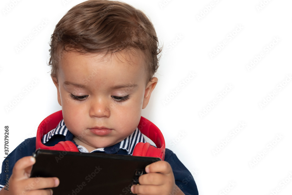 child watching videos on mobile phone with red headphones and dark blue shirt child watching videos on mobile phone with red headphones and dark blue shirt