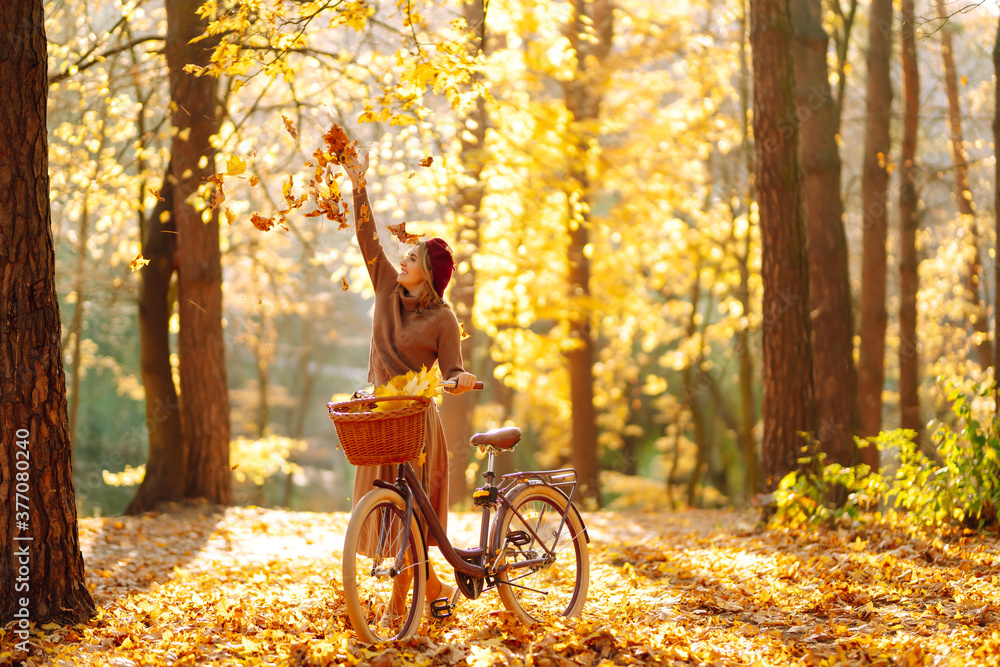 Happy young woman having fun and playing with autumn yellow leaves in autumn park.  Relaxation, enjoying, solitude with nature. - obrazy, fototapety, plakaty 