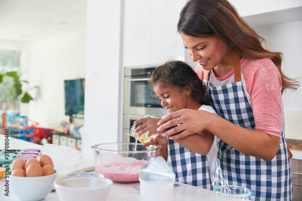 Hispanic Mother And Daughter Having Fun In Kitchen At Making Cake Together