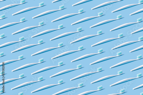 White toothbrush with blue bristles on a blue paper background.