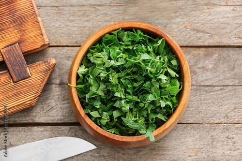 Bowl with fresh parsley on wooden table