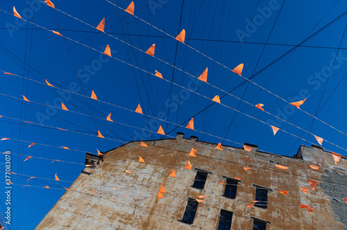 Lots of orange flags on wires against the blue sky and the edge of an abandoned old house photo