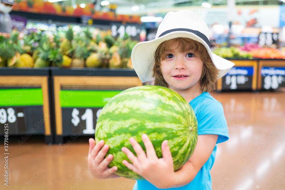 Fototapeta premium Kid holding watermelon in supermarket. Vegetables in store.