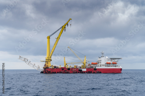 A typical derrick pipelay barge with 3000 metric tonne crane at an oil field during an overcast weather condition