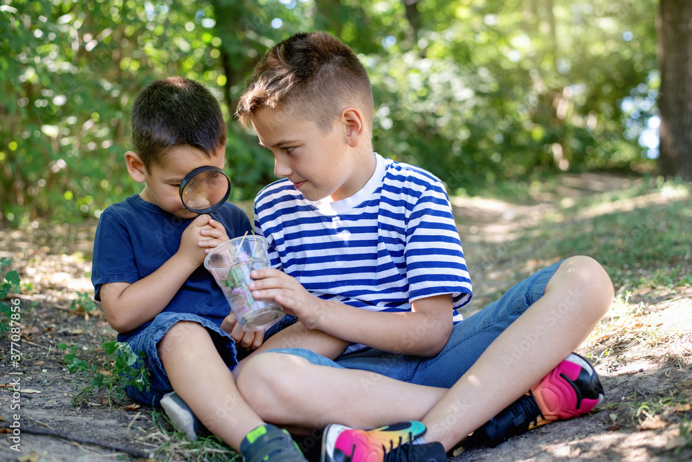 Two little boys look at the plants through a magnifying glass