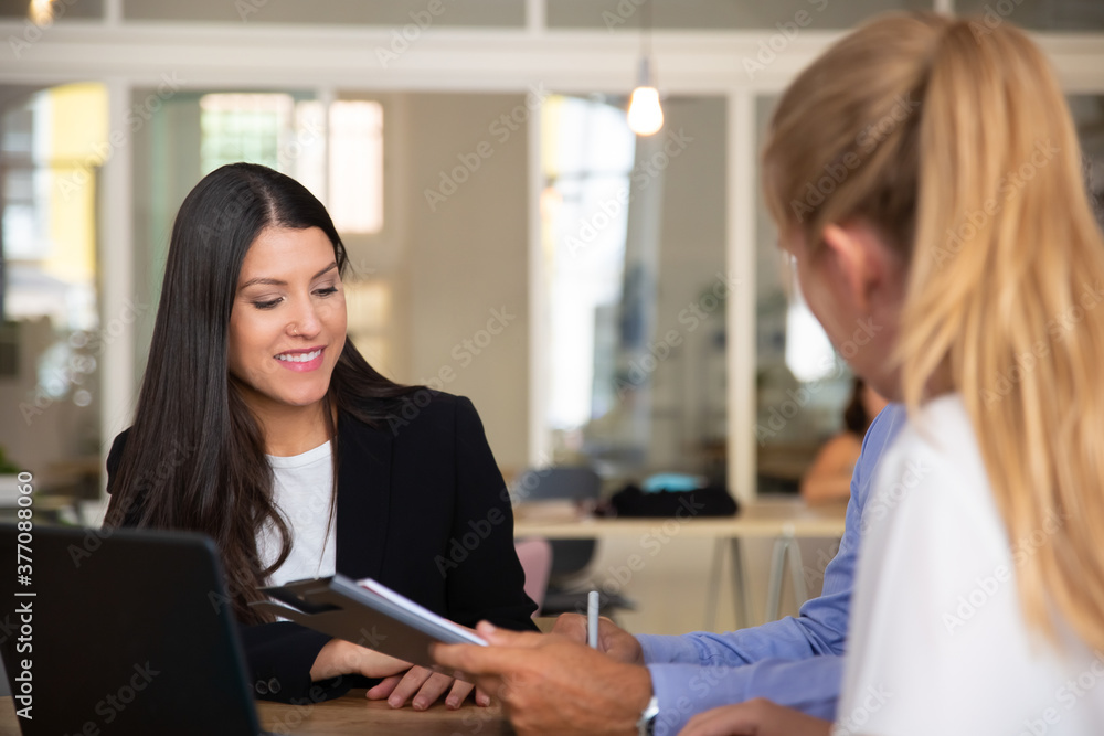 Successful consultant meeting with customers and discussing agreement. Young woman in formal jacket talking to couple with notepad. Business meeting concept Successful consultant meeting with customers and discussing agreement. Young woman in formal jacket talking to couple with notepad. Business meeting concept