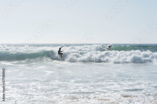 surfers off the coast of portugal catching a wave with foam