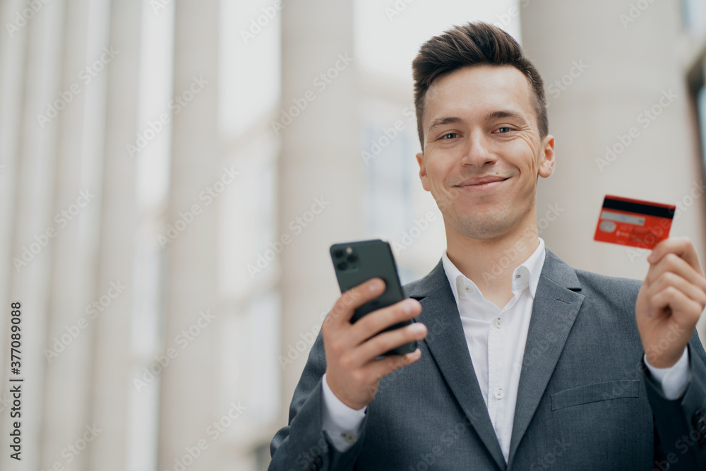 portrait of a man of European appearance. holding a phone and Bank card, wants to pay for purchases in an online store for the family with home delivery portrait of a man of European appearance. holding a phone and Bank card, wants to pay for purchases in an online store for the family with home delivery