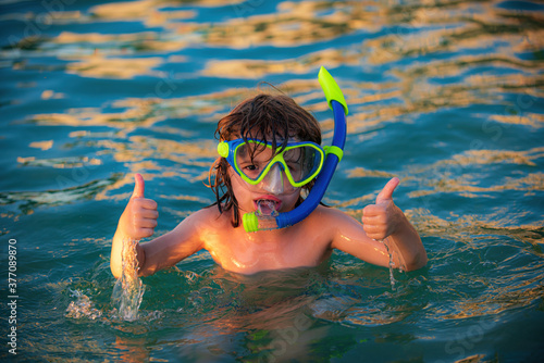 Summer kids holidays. Happy child playing in the sea. Kids having fun on the beach. Kids show gesture thumb up.