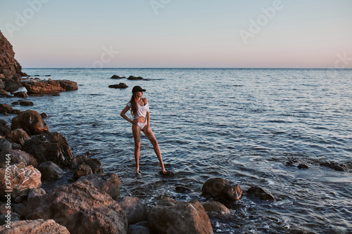 Lady posing on stones in sea. Amazing seaview. Breathtaking seascape. Beauty and relaxation concept. Beach vacation